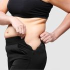 En kvinna som försöker få ihop dragkedjan på sina byxor