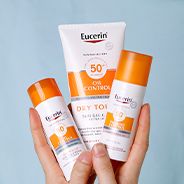 Händer som håller tre solskyddsprodukter från Eucerin